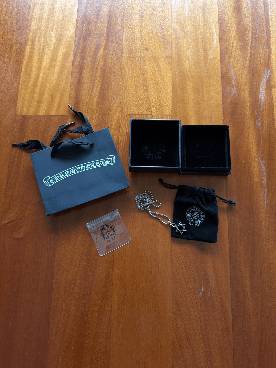 Silver-coloured pendant, chain and packaging